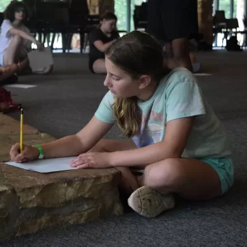young girl at ymca camp lakewood writing a letter to her parents