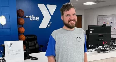 Sam with a large Y logo behind him