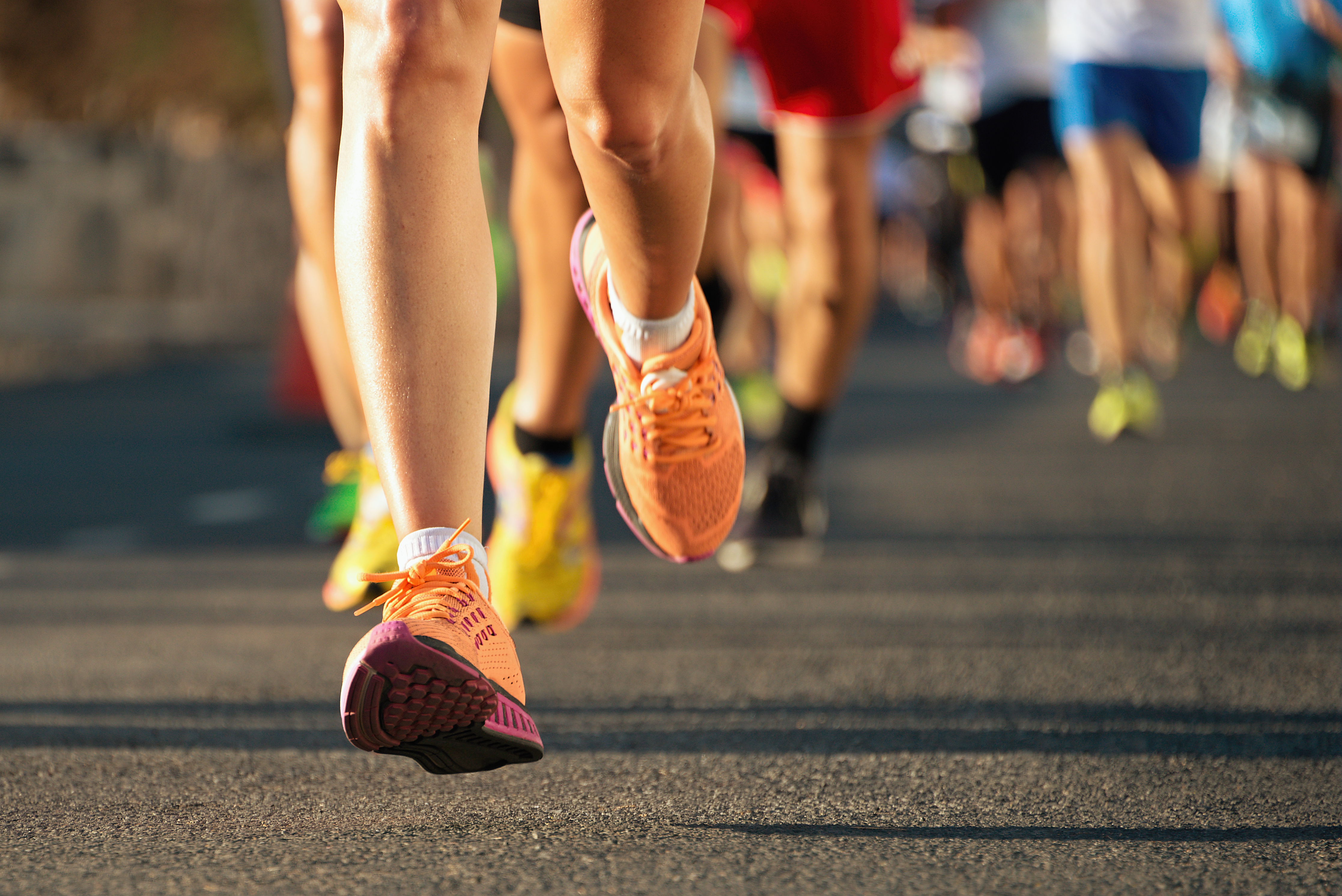 A group of runners shoes hitting the pavement during a race