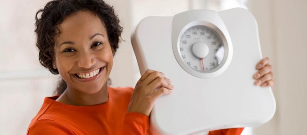 woman smiling holding a scale in her hands