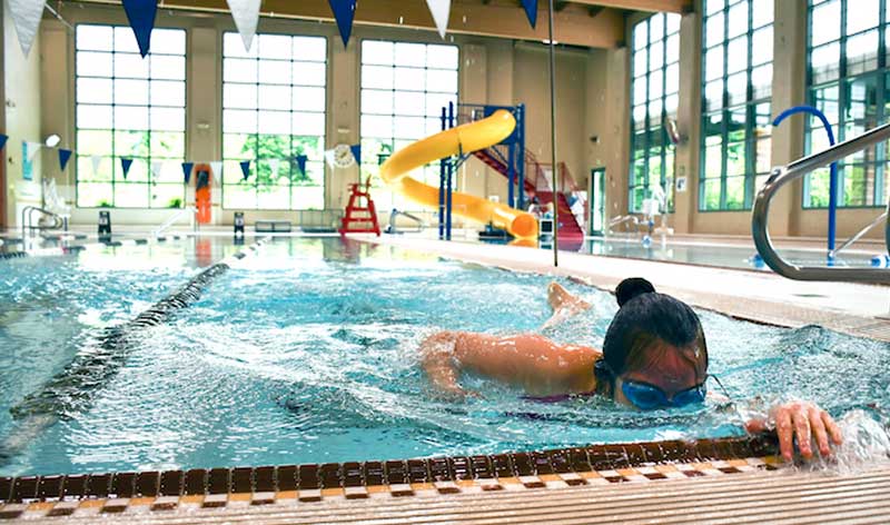 A woman swims laps in a ymca indoor swimming pool