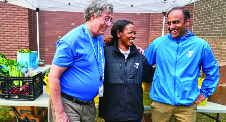 A group of friends smile while having fun at a ymca healthy food distribution event