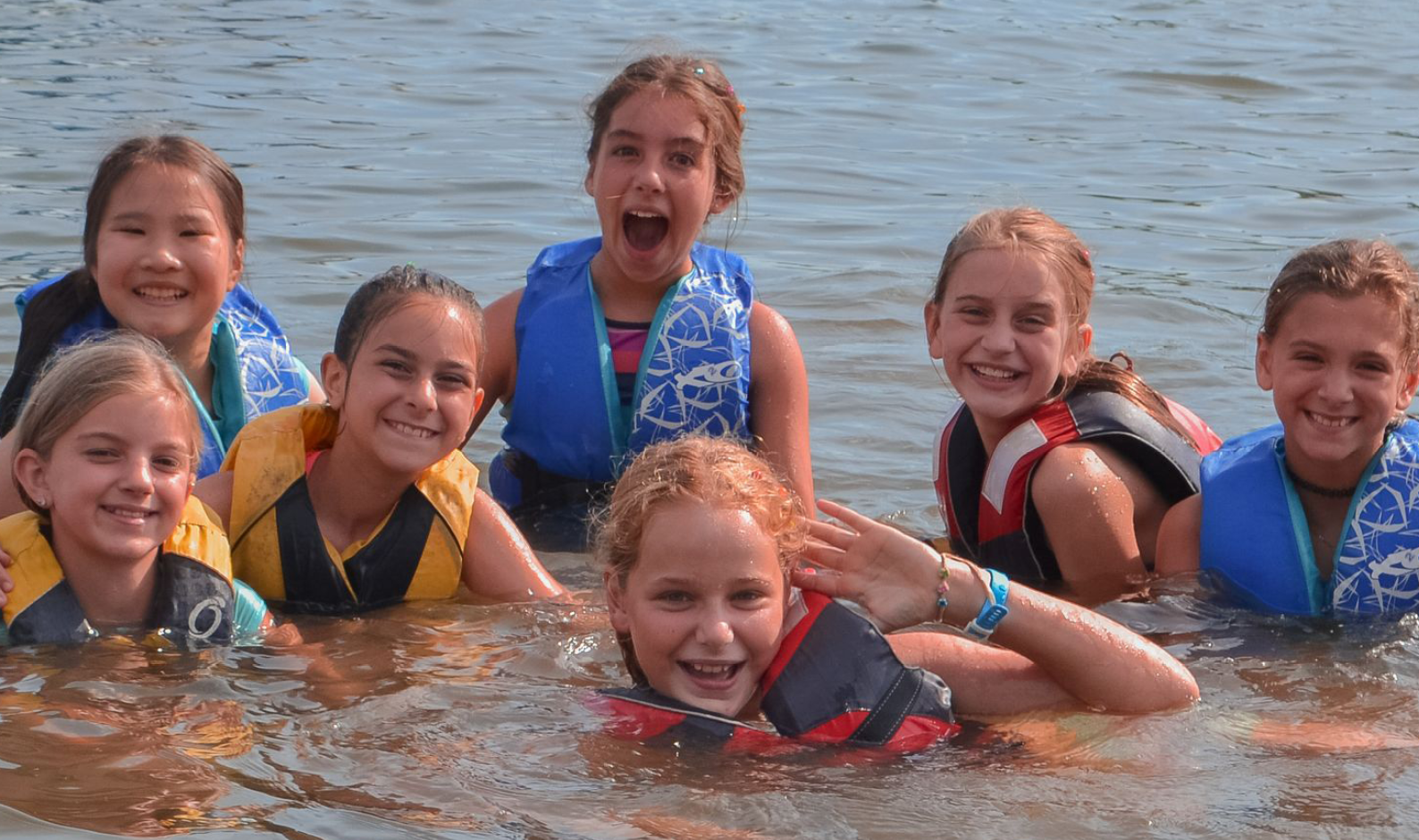group of happy girls swimming in lake