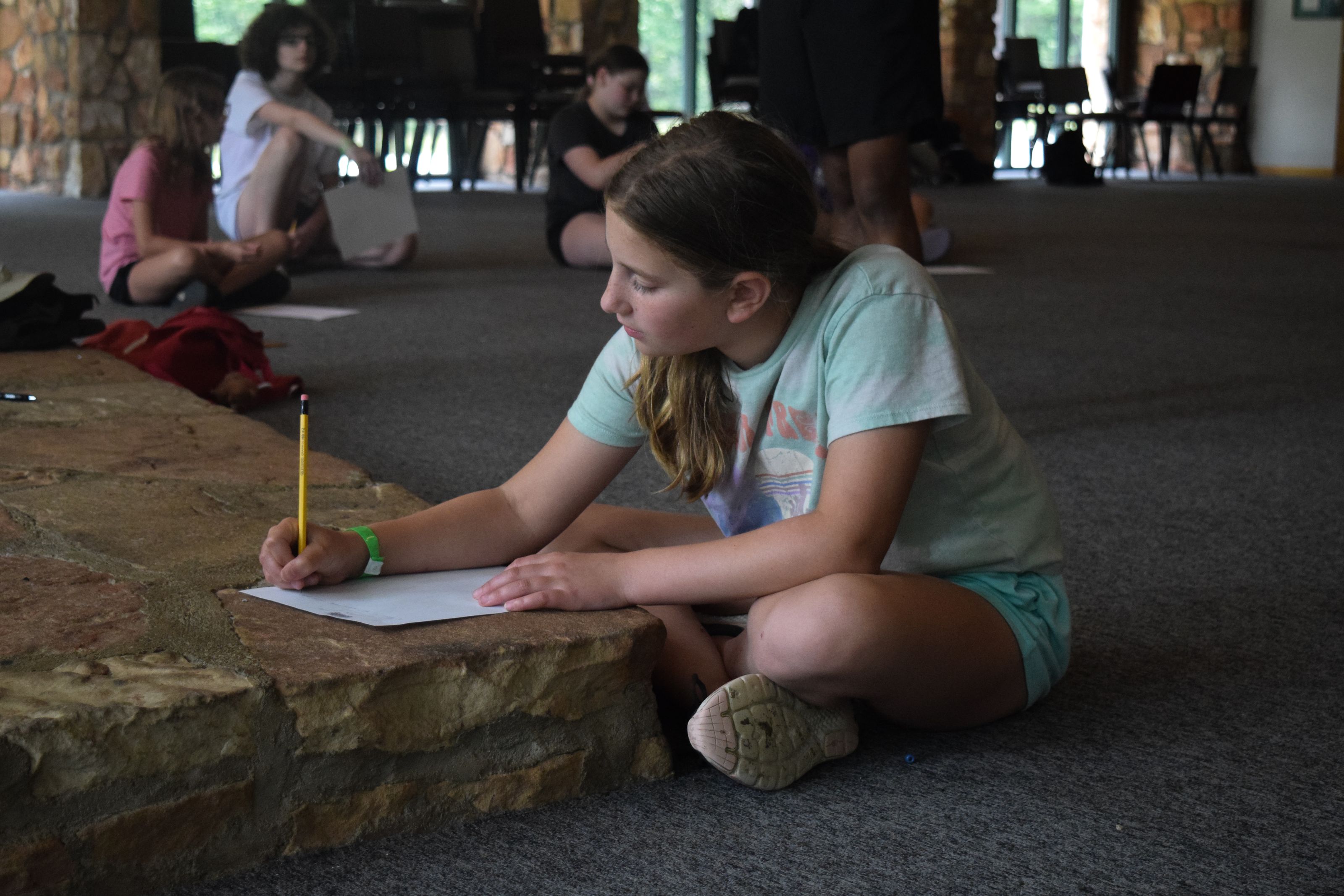 young girl at ymca camp lakewood writing a letter to her parents