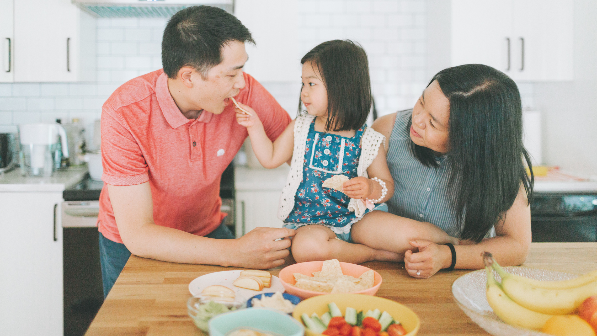 young girl and parents eating snacks together