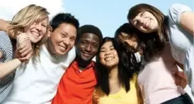 An image of a diverse group of six teenagers gathered together arm-in-arm for a photo at the YMCA.