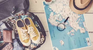 Shoes sitting on a suitcase by a map