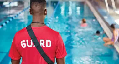A ymca lifeguard monitoring the pool as patrons swim