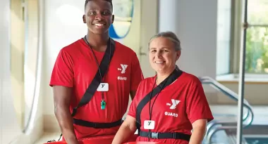 YMCA Lifeguards smiling next to a ymca indoor pool