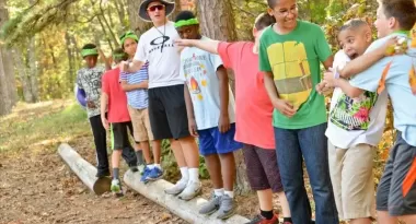 An image taken of a class and teacher doing a teambuilding activity outside during YMCA camp.