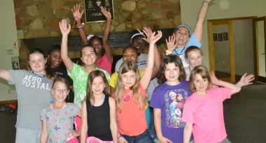 An image of a diverse group of 13 girls at a birthday party held at the YMCA.