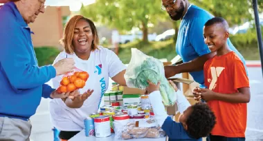 a family volunteers at a ymca food drive and community food delivery service