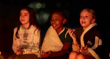 three children sitting by campfire