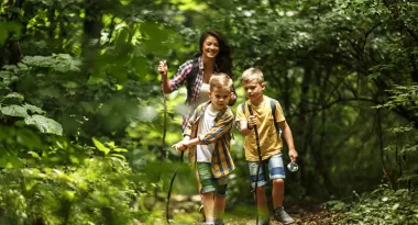 a mother and two boys on a hike in the woods