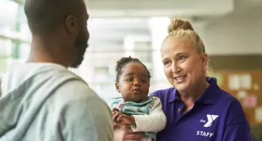 A YMCA Staff member holds a baby just checked into YMCA Child Watch