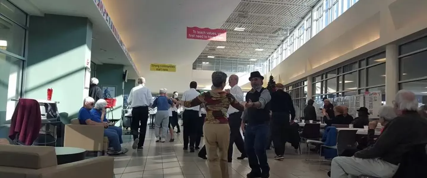 A group of active older adults dance in the ymca lobby