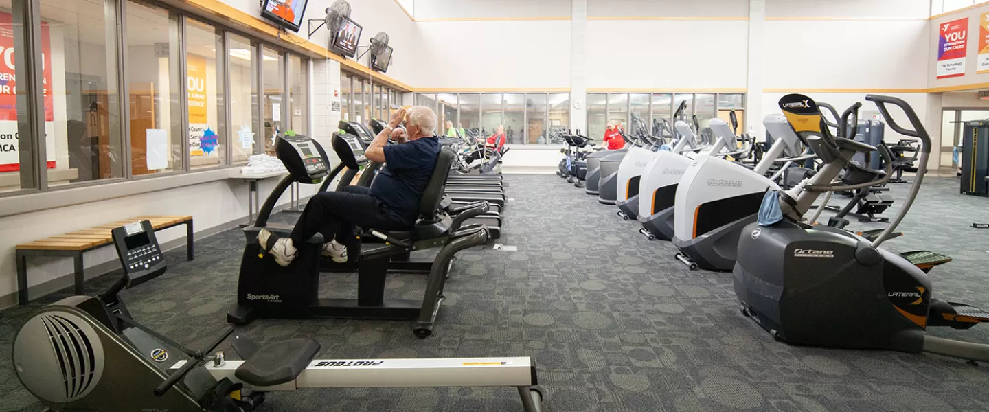 Cardio area with rows of treadmills, ellipticals, and zero-impact trainers. Wide rows between equipment.