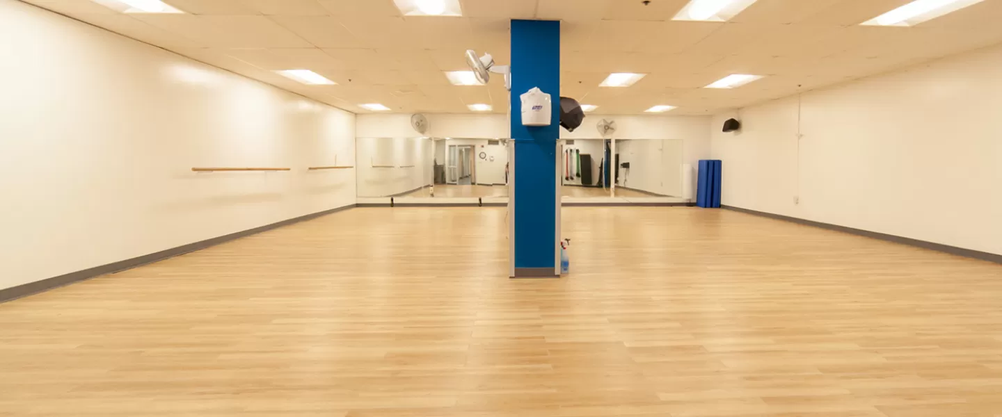 Group exercise room with mirrors on one side. Large, rectangular room with non-slip flooring.