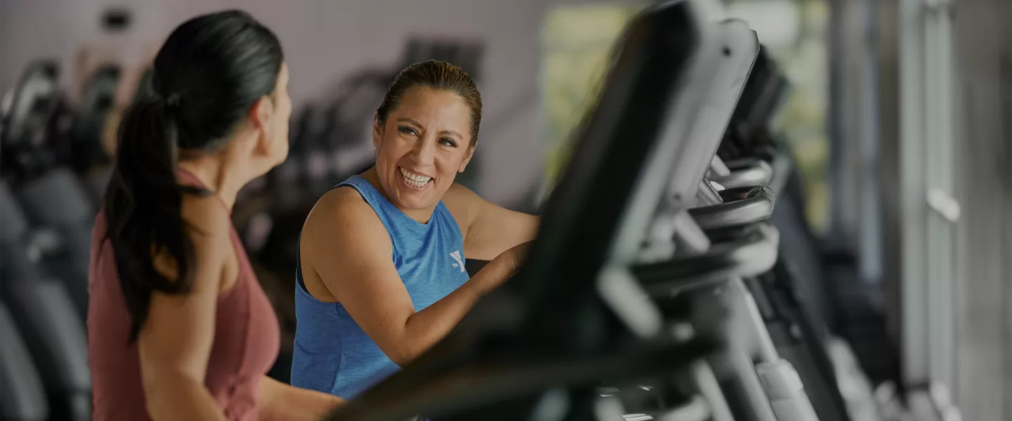 Two Women Laugh as they Workout in a YMCA Fitness Center