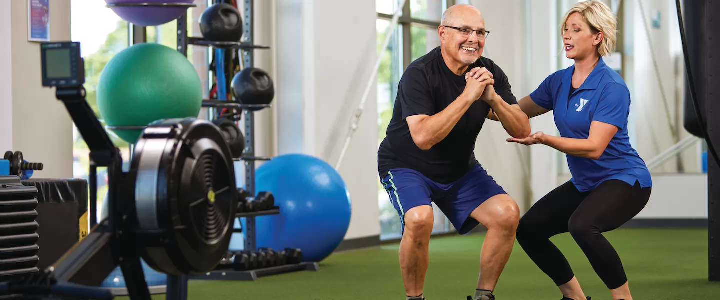 older adult working out with personal trainer at the ymca