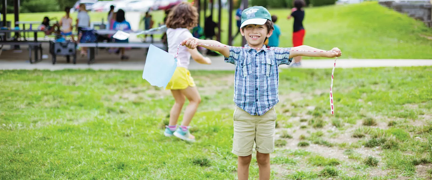 young boy playing with a kite at ymca summer day camp
