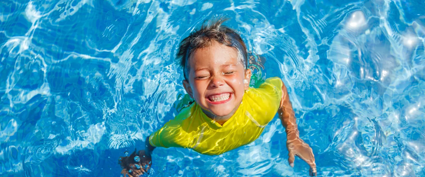 young boy smiling in pool