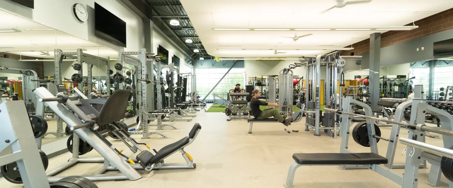 Alternate view of the renovated functional fitness area at Four Rivers YMCA featuring new weight training equipment, turf flooring, updated lighting, and modern design elements