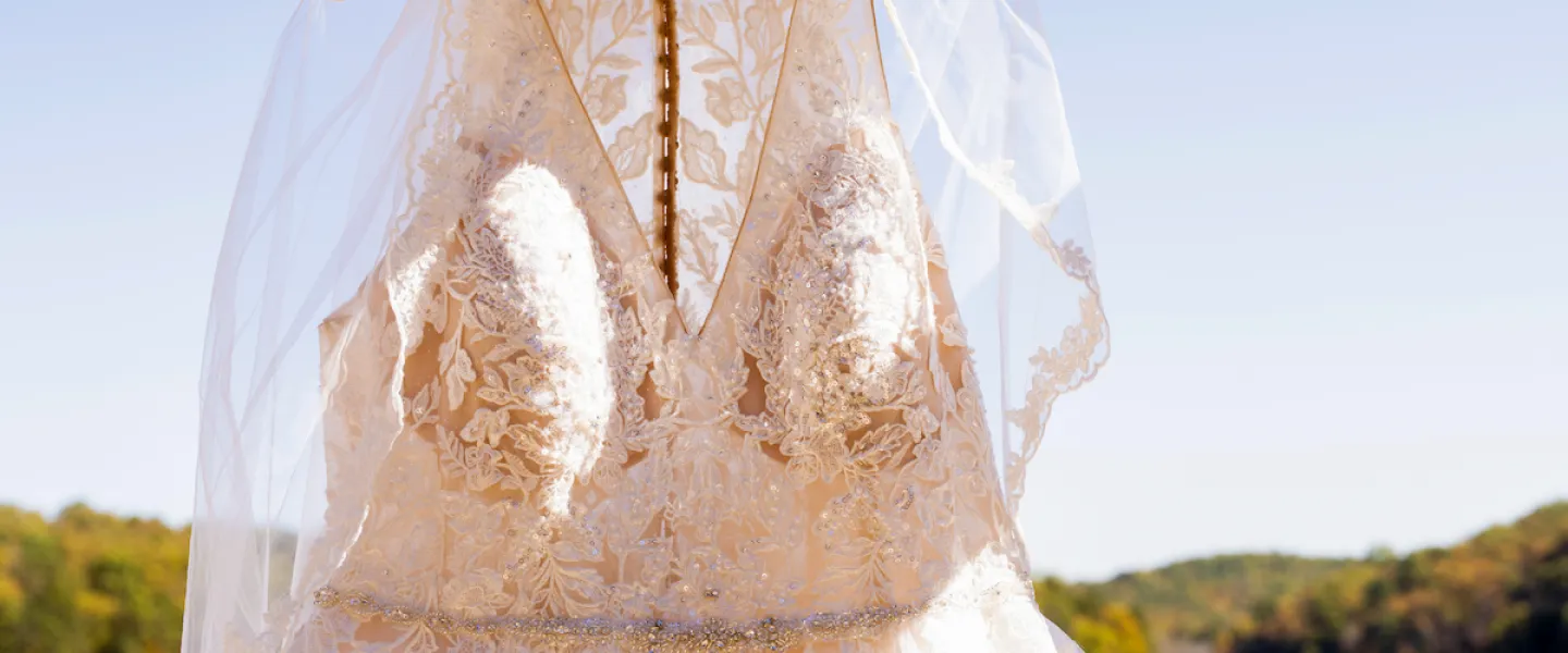 A beautiful white wedding dress hanging in front of Sunnen Lake, ready for the bride.