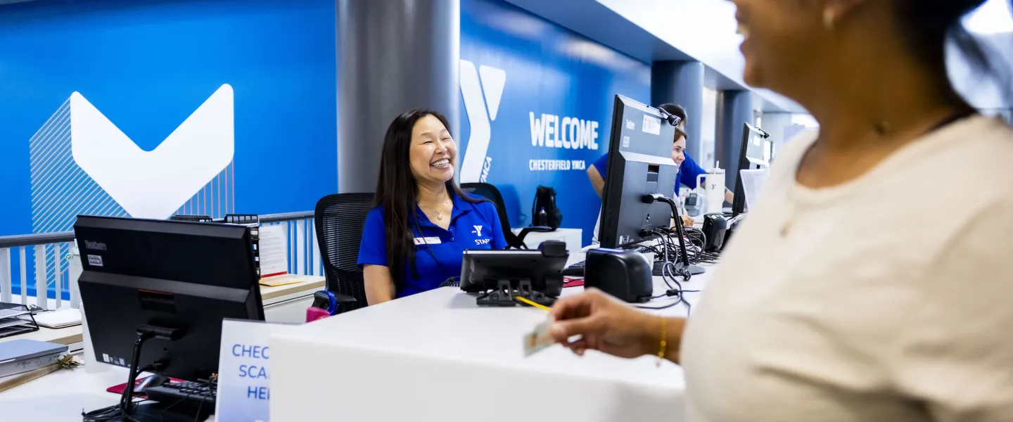 YMCA Welcome Center staff smiling at a YMCA Member as they check into the YMCA.