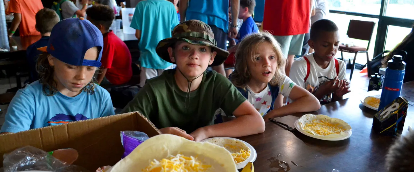 A camper's plate filled with soft and hard shell tacos and seasoned corn inside the dining hall.