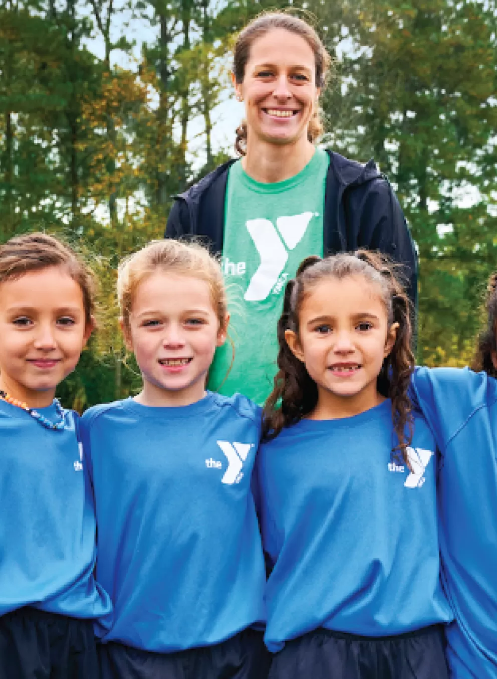 a ymca youth soccer volunteer coach smiles with her girls youth soccer team