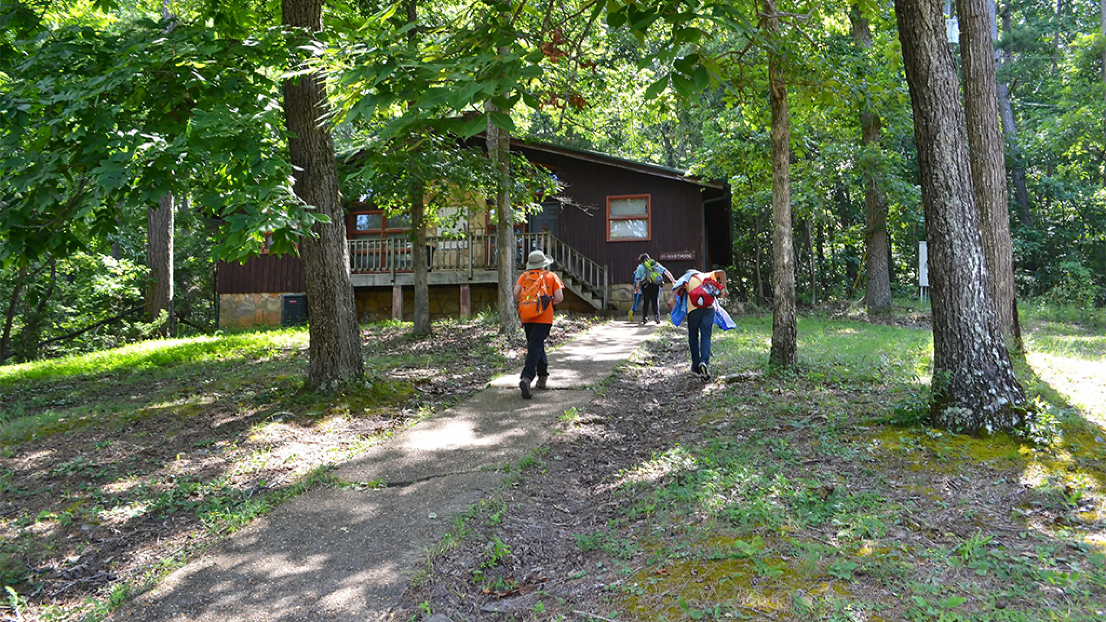 Campers walking towards a YMCA Camp Lakewood Main Camp cabin in the forested woods of Potosi, Missouri