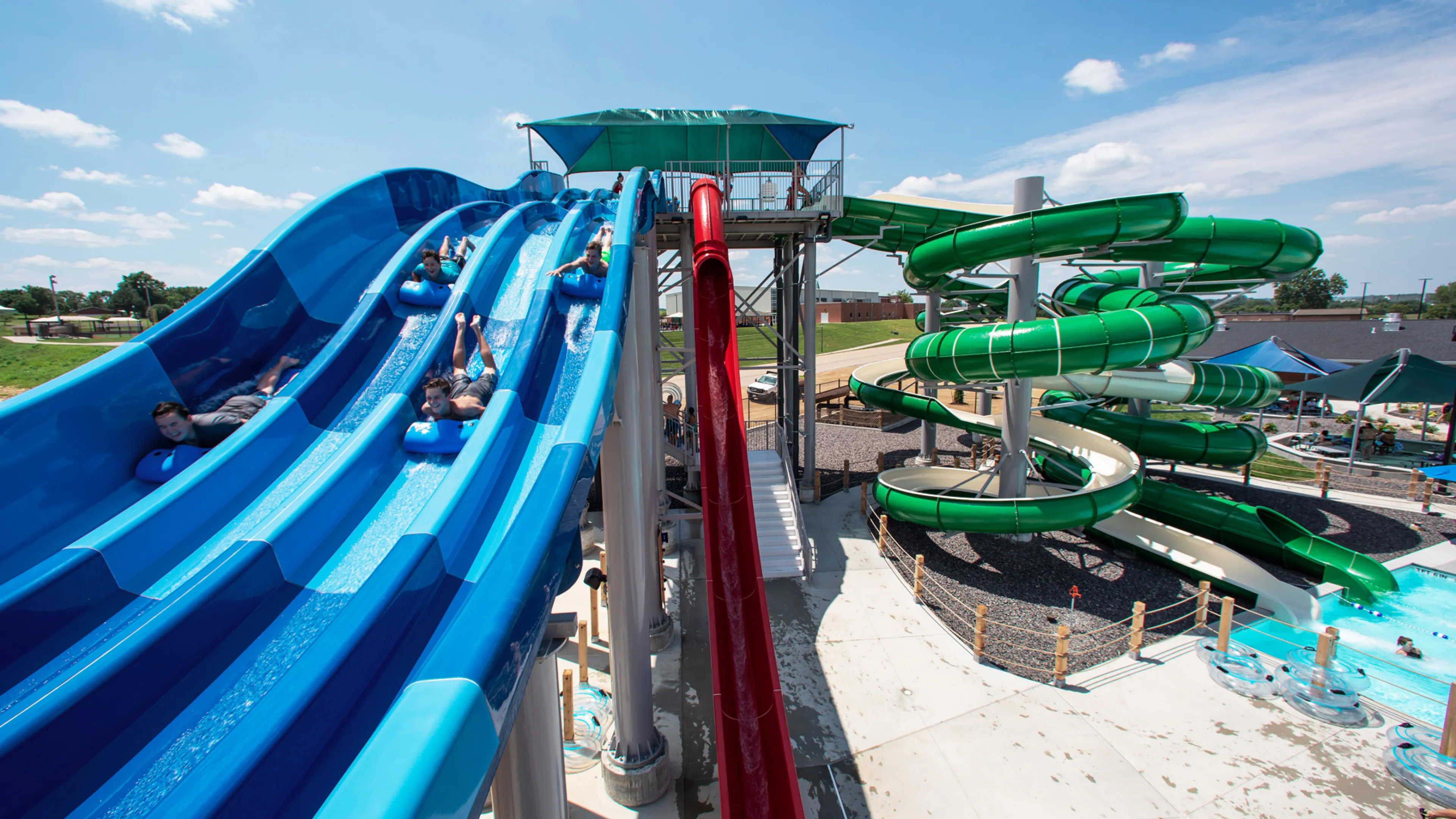 A thrill-seeker speeding down one lane of the multi-lane blue racer water slide, kicking up spray at the River Rapids Waterpark.