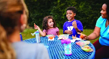 Children sit at a picnic table eating healthy foods that improve bone health