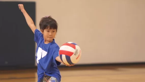 a young girl serves a ymca volleyball