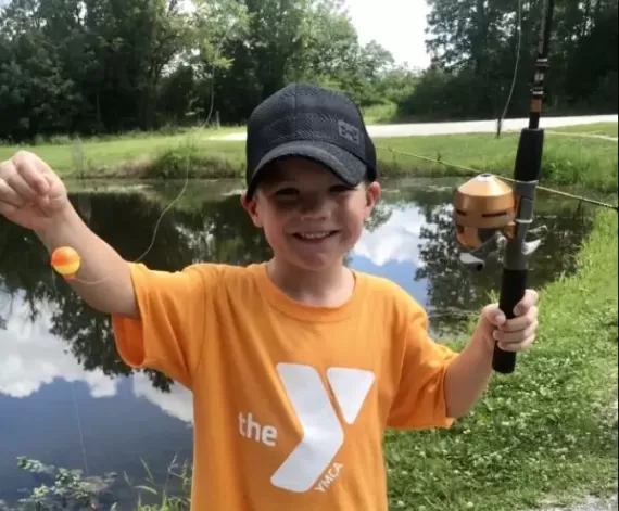 a young boy holds up a fish