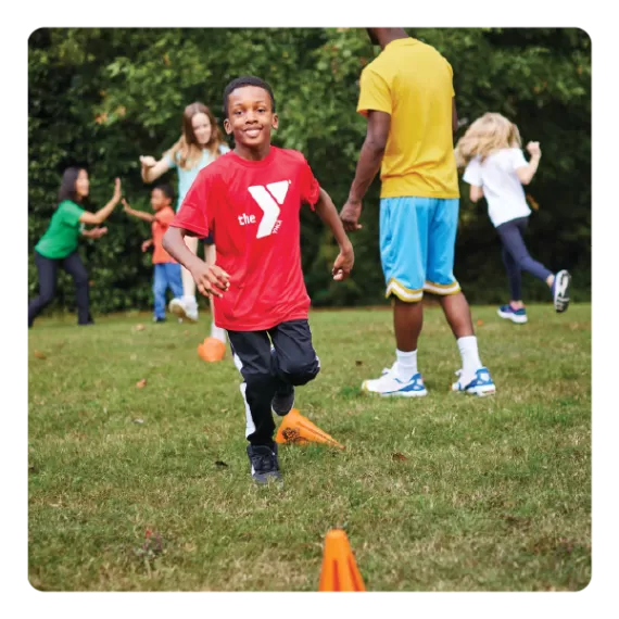 a young boy plays field games having fun at ymca summer day camp