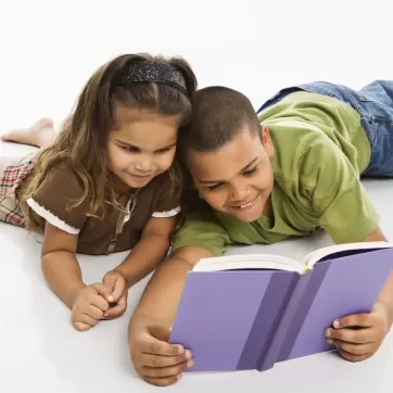 a young boy and a girl reading a book together