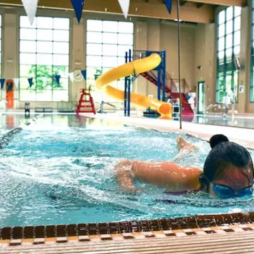 A woman swims laps in a ymca indoor swimming pool