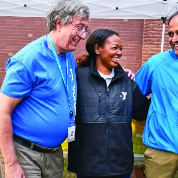 A group of friends smile while having fun at a ymca healthy food distribution event