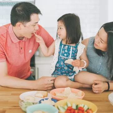 young girl and parents eating snacks together