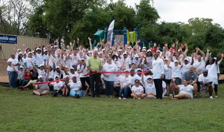 a group of volunteers cheering in front of a playground