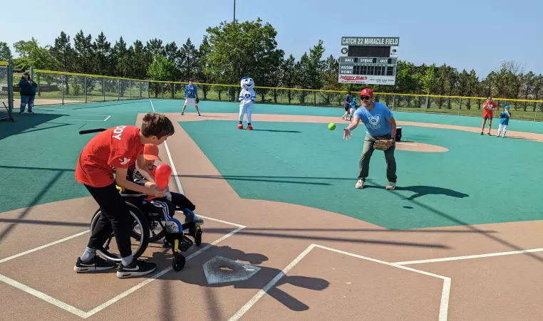 An adaptive sports participant and his buddy bat in an adaptive baseball game.