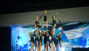 Thumbnail: An image of the Caucasian girls cheer team from the YMCA competing in a group stunt at a local competition.