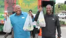 Thumbnail: An image of two African American men posing in front of the YMCA's Metro Market Bus. They are enthusiastically holding up bags of food in their hands.