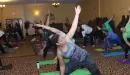 Thumbnail: An image of a large group of African American women doing yoga, posing in the middle of a class provided by the YMCA.	