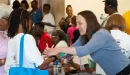 Thumbnail: An image of a Caucasian volunteer at the YMCA's backpack give-away assisting a young African American female and her grandmother. There is a group of middle-aged African American females and males also visible in the background.