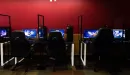 Thumbnail: An image of the computers in the esports arena at the YMCA against a red wall.
