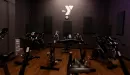 Thumbnail: Dark painted walls with mood lighting. Spin bikes placed throughout room.