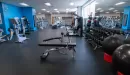 Thumbnail: Spacious functional fitness space with medicine balls, free weights, and benches facing a mirror.